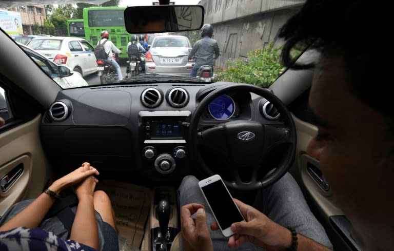 Ankur Bhatia (R), head of marketing at Mahindra Electric Mobility, checks his mobile phone while driving Mahindra's electric car "e2o Plus", in New Delhi