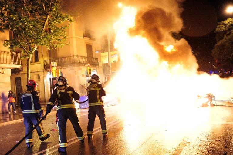 Firefighters hose down burning bin containers in Barcelona on May 28, 2014 on the third night of clashes following evictions of activists