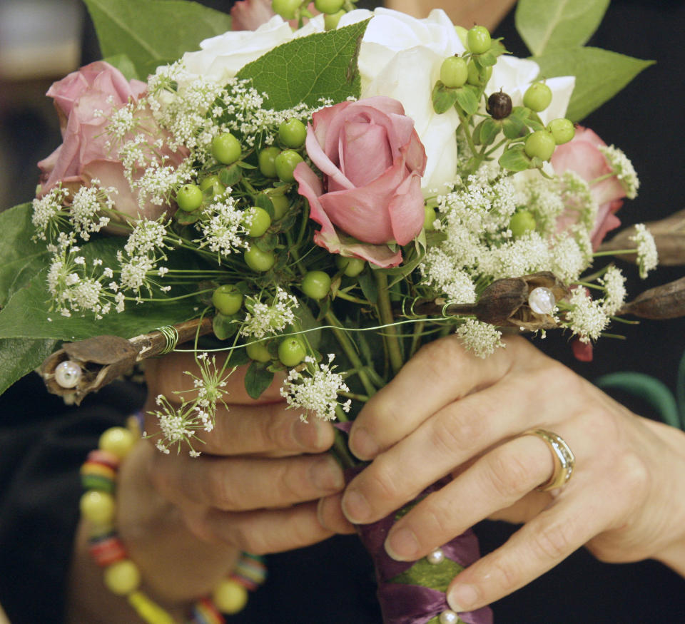 FILE - In this Thursday, Nov. 30, 2006, file photo, Leanne Kesler, the president of the Floral Design Institute is shown working with a bridal bouquet in Portland, Ore. A new study from Pew Research Center released Tuesday, Oct. 5, 2021, underscores the economic advantages of being married, especially as the share of single people in the U.S. has grown over the past three decades. (AP Photo/Rick Bowmer, File)