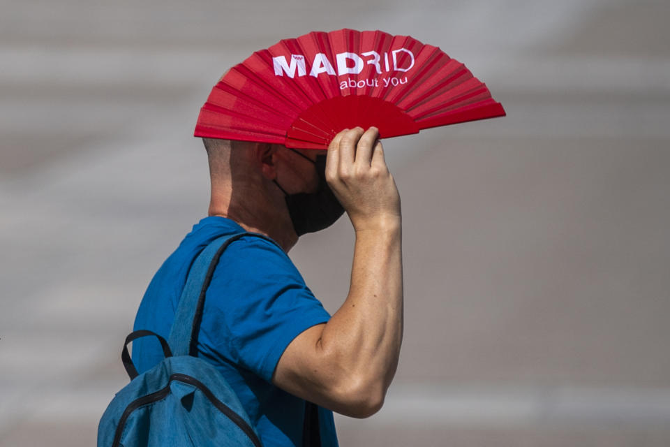 A man protects himself from the sun with a fan during a heatwave in Madrid, Spain, Friday, Aug. 13, 2021. Stifling heat is gripping much of Spain and Southern Europe, and forecasters say worse is expected to come. (AP Photo/Andrea Comas)