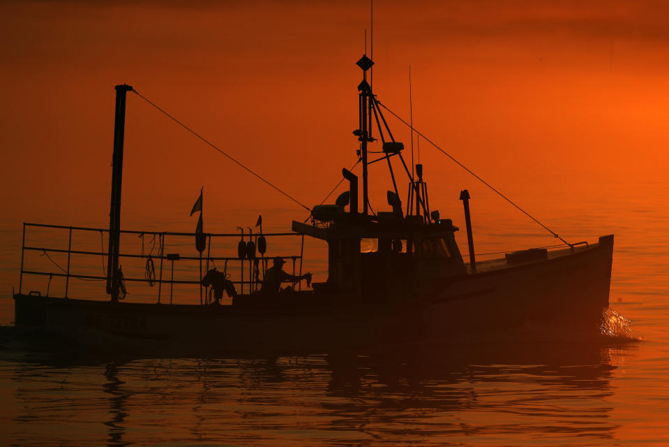 FILE - In this July 2019 file photo, a lobster boat heads out to sea at dawn off South Portland, Maine. It’s a slow lobster season so far in Maine, but fishermen are still hopeful it’ll be a good one. The harvest of crustaceans in America’s biggest lobstering state is usually in full swing by July, but fishermen say they aren’t catching much. (AP Photo/Robert F. Bukaty, File)