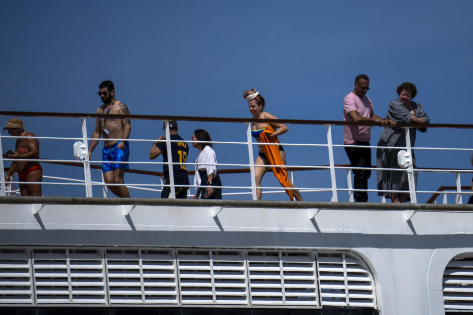 Passengers are photographed on the cruise ship MSC Armony, moored in the port of Barcelona, Spain, Wednesday, April 3, 2024. Authorities said Wednesday that a group of 69 Bolivians are not being allowed to disembark from a cruise ship in the Spanish northeastern port of Barcelona because they lack valid documents to enter the European Union's Schengen area. (AP Photo/Emilio Morenatti)