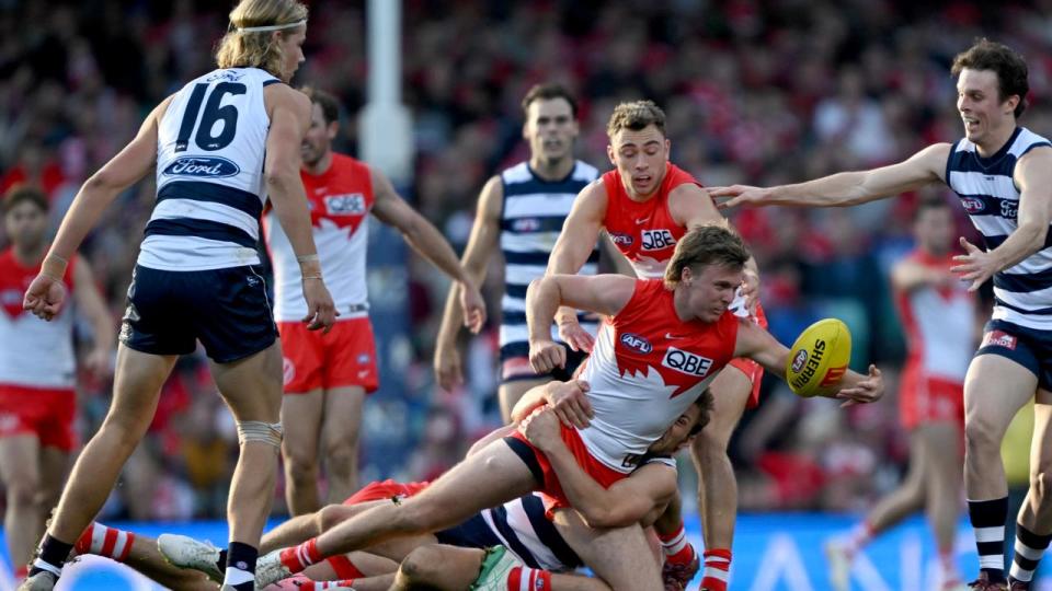 Swan Peter Ladhams is tackled by Geelong defenders.