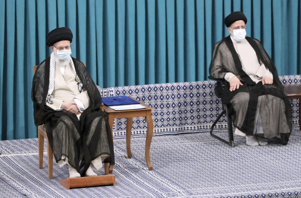 In this photo released by an official website of the office of the Iranian supreme leader, Supreme Leader Ayatollah Ali Khamenei, left, sits in an endorsement ceremony to give his official seal of approval to newly elected President Ebrahim Raisi, right, in Tehran, Iran, Tuesday, Aug. 3, 2021. (Office of the Iranian Supreme Leader via AP)