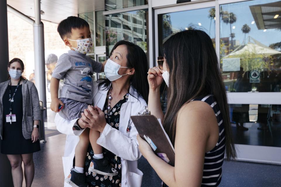 A doctor holds a masked child in her arms.