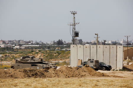 An Israeli tank and a military vehicle can be seen next to a security barrier near the border between Israel and the Gaza Strip, Israel March 18, 2018. REUTERS/Amir Cohen