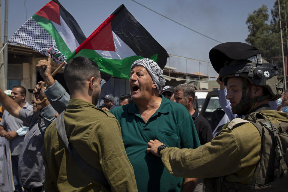 A Palestinian argues with Israeli soldiers during a protest against the creation of a new road for Israeli settlers, near the Palestinian village of Beita, north of the West Bank city of Nablus, Wednesday, Aug. 25, 2021. (AP Photo/Majdi Mohammed)