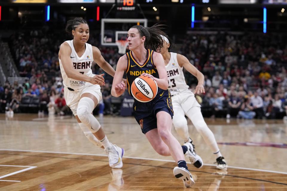 Fever guard Caitlin Clark (22) drives past two Dream defenders to the basket during a preseason game Thursday in Indianapolis