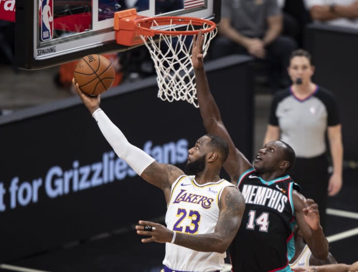 Los Angeles Lakers forward LeBron James (23) shoots past Memphis Grizzlies center Gorgui Dieng (14) during the first half of an NBA basketball game Sunday, Jan. 3, 2021, in Memphis, Tenn. (AP Photo/Wade Payne)