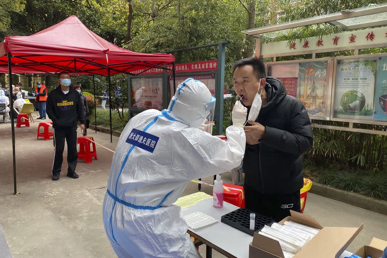 En esta imagen, distribuida por la agencia noticiosa Xinhua, un trabajador sanitario de la provincia de Zhejiang toma una muestra bucal a una persona para una prueba de detección del coronavirus, en el distrito de Pudong, en el este de la ciudad china de Shanghai, el 28 de marzo de 2022