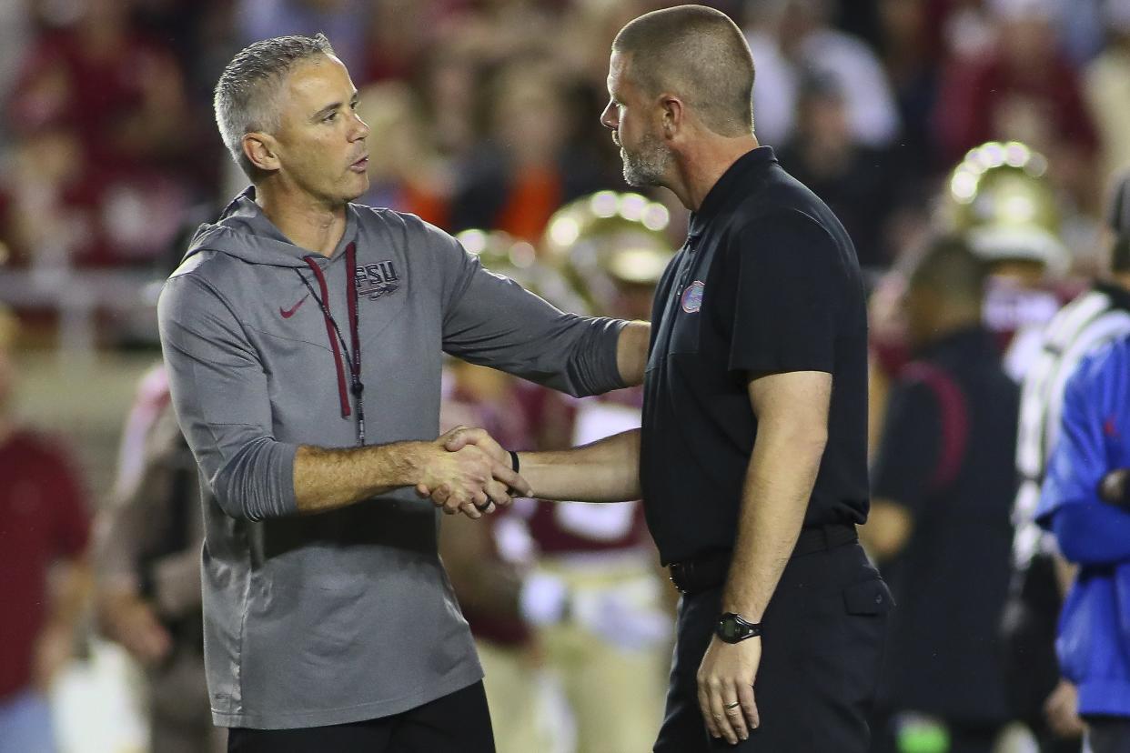 Florida State football coach Mike Norvell (L) and Florida coach Billy Napier (R), shaking hands before the FSU-Florida game, will both be expected to have their programs reaching the expanded 12-team College Football Playoff most years when that format begins in 2024.