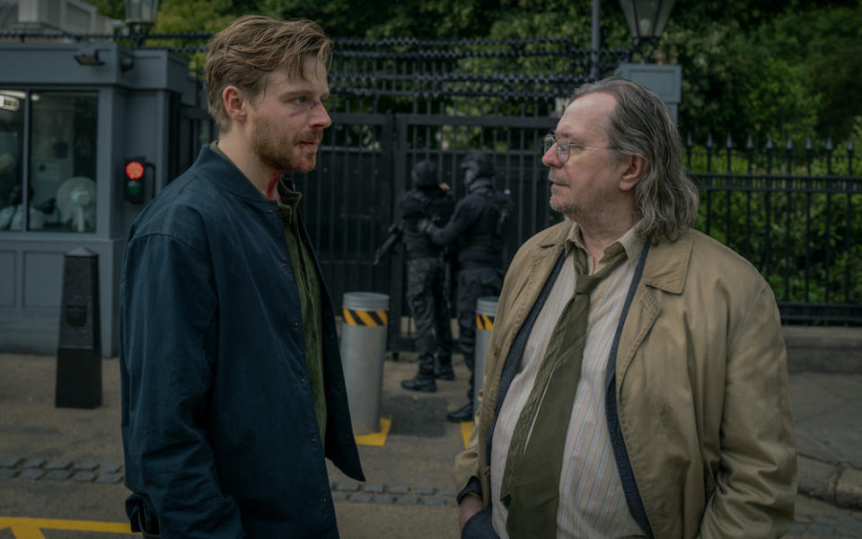 Jack Lowden and Gary Oldman in 'Slow Horses,' talking on the street, Jack with a bloody face