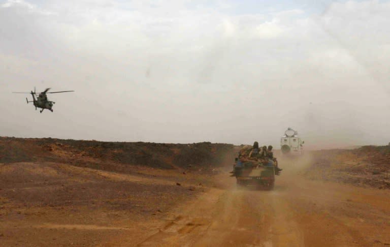 A helicopter guards an official car on the road from Gao to Kidal in Mali