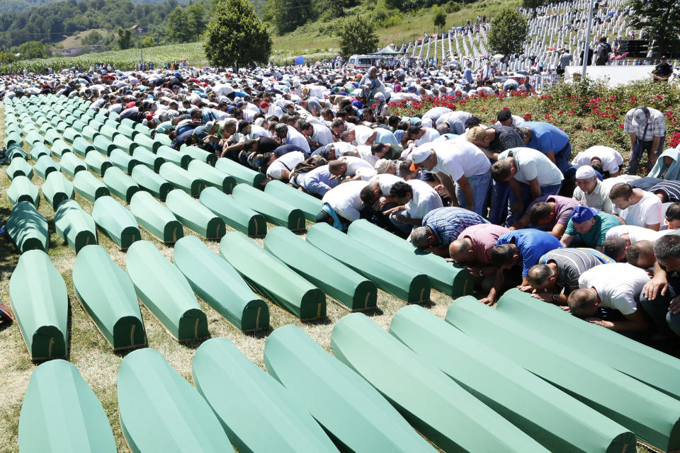 FILE - A Monday, July 11, 2016 file photo of Bosnian people saying prayers in front of coffins during a funeral ceremony for the 127 victims at the Potocari memorial complex near Srebrenica, 150 kilometers (94 miles) northeast of Sarajevo, Bosnia and Herzegovina. A Bosnian Serb leader has wrongly called the 1995 Srebrenica massacre, where over 8,000 Muslim men and boys were killed by Bosnian Serb troops, "a fabricated myth." Milorad Dodik, head of Bosnia's multi-ethnic joint presidency, spoke during a conference discussing war crimes. His comments defy international court rulings that said genocide was committed in the eastern Bosnian enclave and have angered Bosnian Muslims. (AP Photo/Amel Emric, File)