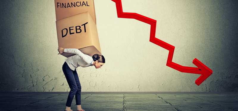 A woman holding boxes reading financial and debt on her back standing next to a falling line chart.