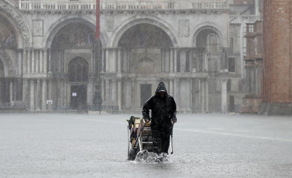 A greengrocer carries his cart as the water begins to flood St. Mark's Square on the occasion of a high tide, in Venice, Italy, Tuesday, Nov. 12, 2019. (Photo: Luca Bruno/AP)