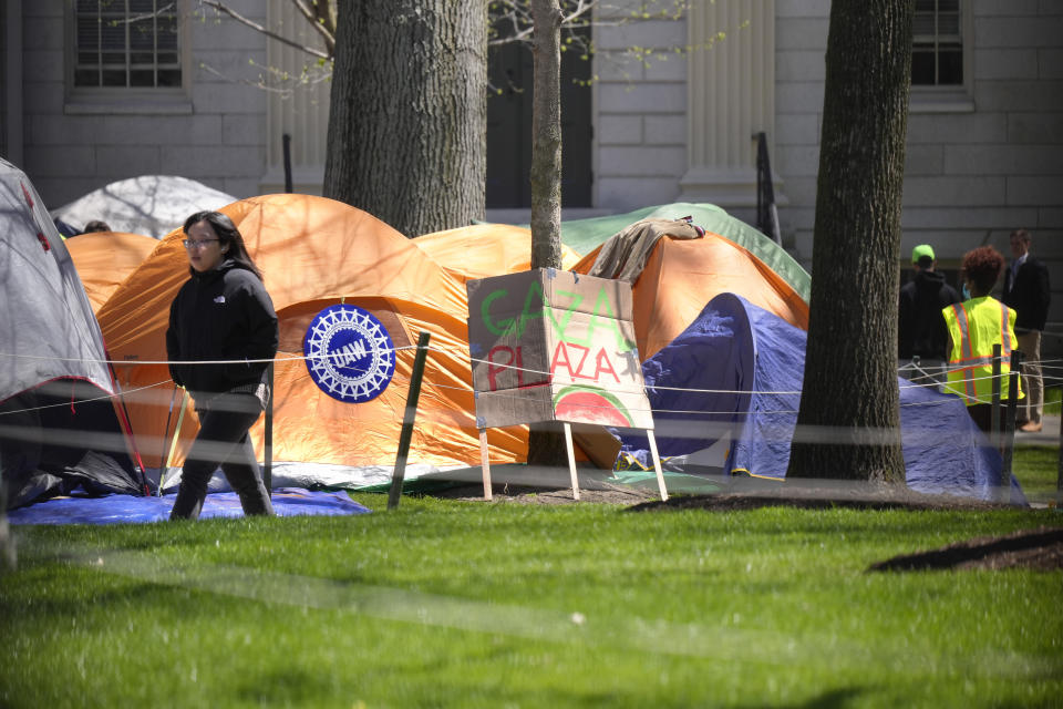 Una mujer camina junto a un campamento de protesta contra la guerra entre Israel y Hamás en Harvard Yard, en el campus de la Universidad de Harvard, el jueves 25 de abril de 2024, en Cambridge, Massachusetts. (AP Foto/Steven Senne)