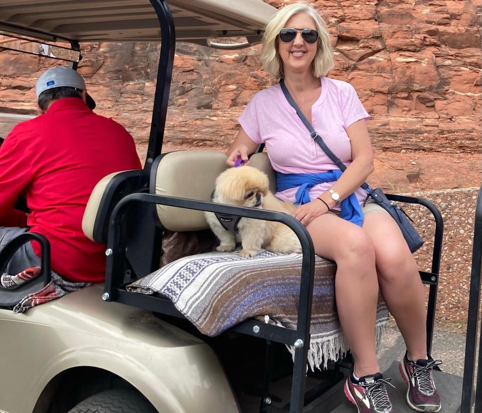 Author Courtenay Rudzinski with one of her dogs on the back of a golf cart in Arizona