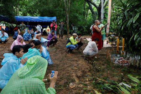 A Buddhist monk and relatives pray near Tham Luang caves during a search for 12 members of an under-16 soccer team and their coach, in the northern province of Chiang Rai, Thailand, June 27, 2018. REUTERS/Soe Zeya Tun