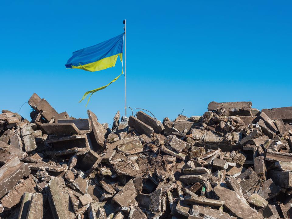 Ukraine flag over rubble.