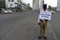 A traffic police personnel holds a placard as he stands guard on a deserted road junction during a one-day Janata (civil) curfew imposed amid concerns over the spread of the COVID-19 novel coronavirus, in Secunderabad, the twin city of Hyderabad, on March 22, 2020. (Photo by NOAH SEELAM / AFP) (Photo by NOAH SEELAM/AFP via Getty Images)