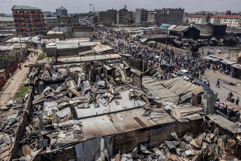 La gente se reúne para evaluar los daños junto a una zona de casas y tiendas demolidas y quemadas, el día después de que una explosión de gas provocara graves daños en la zona de Embakasi de Nairobi el 2 de febrero de 2024.