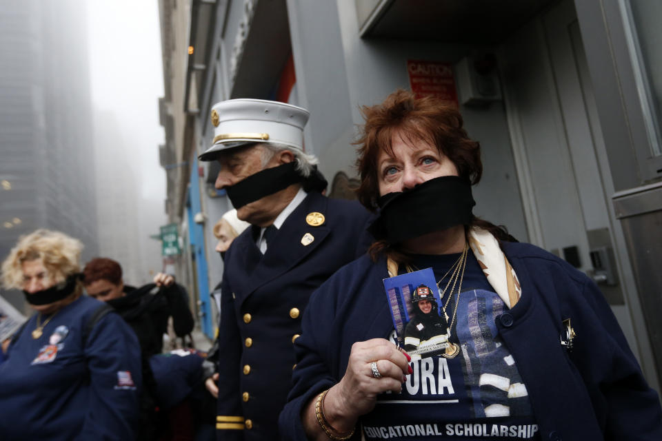 Maureen Santora holds a photo of her son, firefighter Christopher Santora, as she and other family members of victims of the of the Sept. 11, 2001 attacks wear black gags over their mouths in protest of the transfer of unidentified remains of those killed at the World Trade Center from the Office of the Chief Medical Examiner to the World Trade Center site, Saturday, May 10, 2014, in New York. The remains will be transferred to an underground repository in the same building as the National September 11 Memorial Museum. (AP Photo/Jason DeCrow)