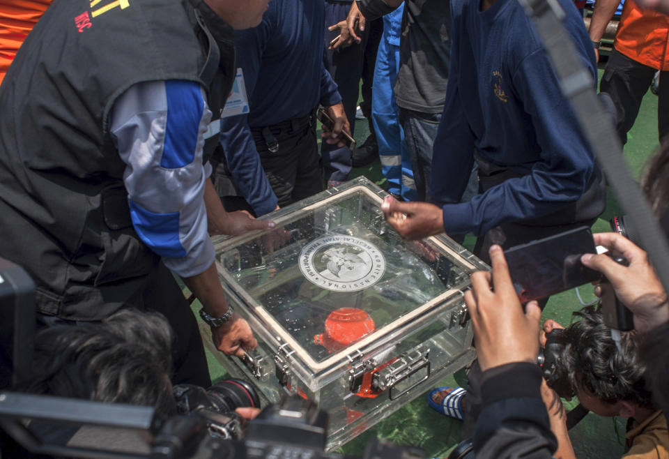 FILE - In this Thursday, Nov. 1, 2018, file photo, members of the National Transportation Safety Committee lift a box containing the flight data recorder from a crashed Lion Air jet onboard a rescue ship anchored in the waters of Tanjung Karawang, Indonesia. Lion Air pilots struggled to maintain control of their Boeing jet as an automatic safety system in the aircraft repeatedly pushed the plane's nose down, according to a draft of a preliminary report by Indonesian officials who are looking into the deadly crash. (AP Photo/Fauzy Chaniago, File)