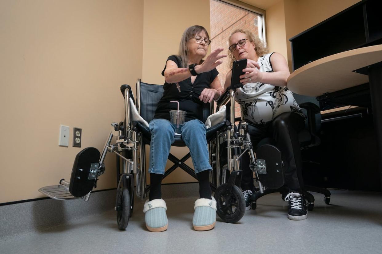 Sharon Dubiel, with the CIUSSS de l’Ouest-de-l’île-de-Montréal, helps patient Danielle Lacasse, left, understand her new health-monitoring devices.  (Ivanoh/DemersRadio-Canada - image credit)