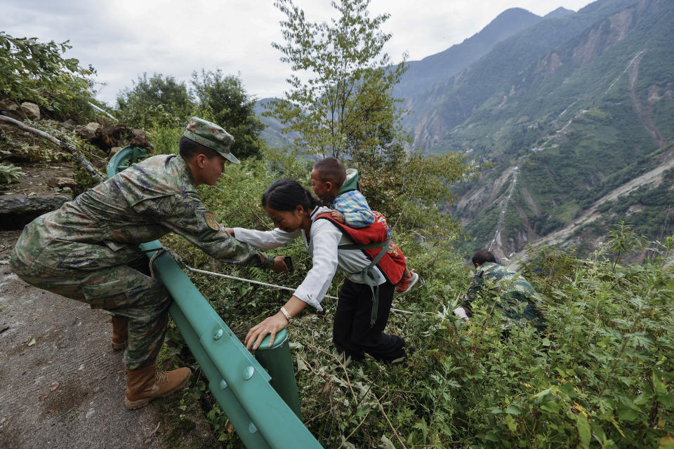 In this photo released by Xinhua News Agency, soldiers help villagers to evacuate from a damaged mountain road following an earthquake in Detuo Town of Luding County, southwest China's Sichuan Province on Sept. 6, 2022. Authorities in southwestern China's Chengdu have maintained strict COVID-19 lockdown measures on the city of 21 million despite a major earthquake that killed dozens of people in outlying areas. (Shen Bohan/Xinhua via AP)