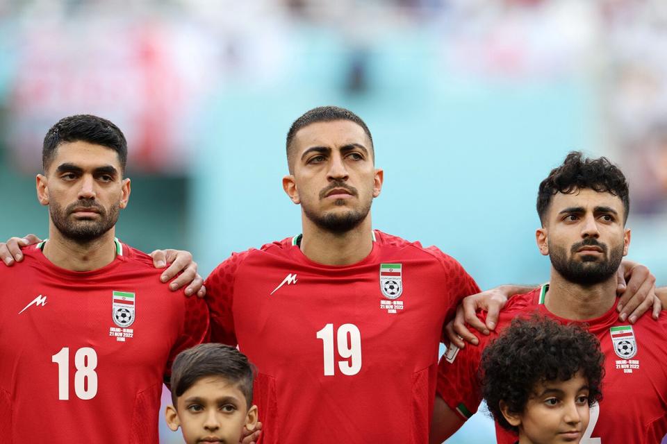 (FromL) Iran's midfielder #18 Ali Karimi, Iran's defender #19 Majid Hosseini and Iran's defender #02 Sadegh Moharrami listen to the national anthem ahead of the Qatar 2022 World Cup Group B football match between England and Iran at the Khalifa International Stadium in Doha on November 21, 2022.