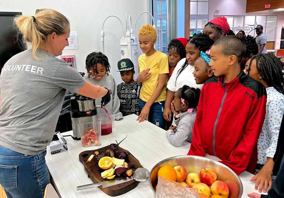 A volunteer with Natural Freedom Farm discusses nutrients of fruits and vegetables during a visit with students at Positive Tomorrows. The nonprofit runs an elementary for families dealing with lack of housing.