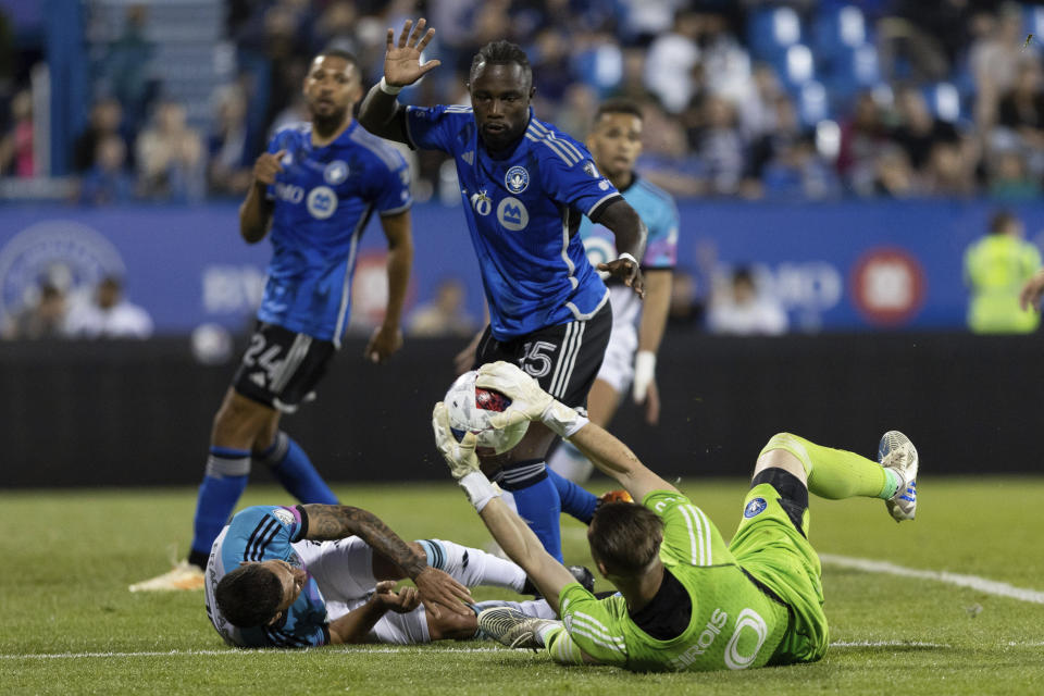 CF Montreal goalkeeper Jonathan Sirois, bottom right, saves the ball after being knocked to the ground by Minnesota United midfielder Franco Fragapane, bottom left, as CF Montreal's Zachary Brault-Guillard (15) looks on during second-half MLS soccer game action in Montreal, Saturday, June 10, 2023. (Evan Buhler/The Canadian Press via AP)