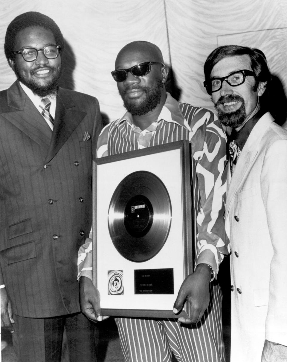 Stax Records executives Al Bell, left, and Jim Stewart, right, present singer and composer Isaac Hayes with a framed record of his album "Hot Buttered Soul" in 1969.