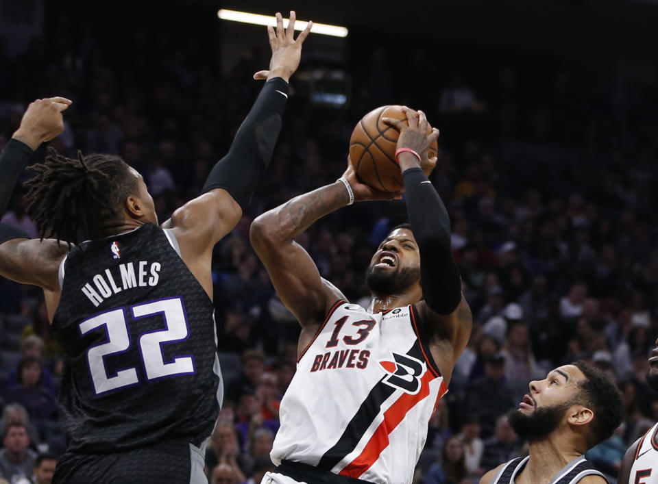 Los Angeles Clippers forward Paul George, center, goes up for a shot between Sacramento Kings' Richaun Holmes, left, and Cory Joseph, right, during the first half of an NBA basketball game in Sacramento, Calif., Tuesday, Dec. 31, 2019. (AP Photo/Rich Pedroncelli)