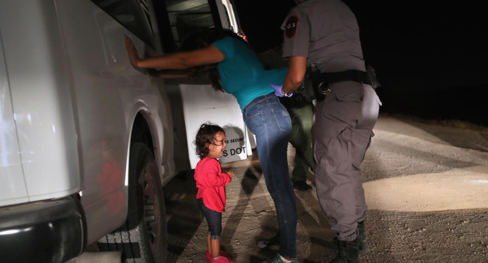 A two-year-old Honduran asylum seeker cries as her mother is searched and detained near the US-Mexico border on June 12. Source: Getty