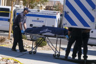 Los Angeles County Coroner officials remove a body from a home where five bodies were found dead, in the city of Lancaster in the high desert Antelope Valley north of Los Angeles, Monday, Nov. 29, 2021. A Los Angeles County Sheriff's Department statement says deputies found a woman, a girl and three boys with gunshot wounds and paramedics pronounced them dead at the scene. The department says the children's father showed up at the Lancaster sheriff's station and was arrested on suspicion of five murders after being interviewed by detectives. (AP Photo/Ringo H.W. Chiu)