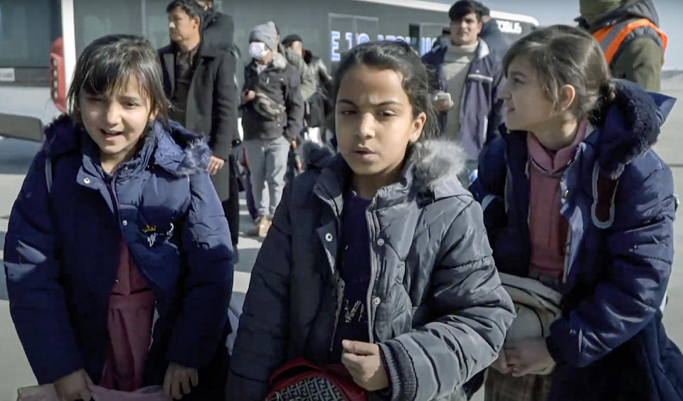 In this photo released by the Russian Defense Ministry Press Service, children wait to board the Russian Military Il-76 cargo planes at the airport in Kabul, Afghanistan, Saturday, Dec. 18, 2021. Russian military transport planes have delivered a shipment of humanitarian supplies to Afghanistan and flew back 200 Russians, Afghan students and others. The Russian Defense Ministry said that three Il-76 cargo planes will make stopover in Tajikistan and Kyrgyzstan before flying to Moscow. (Russian Defense Ministry Press Service via AP)