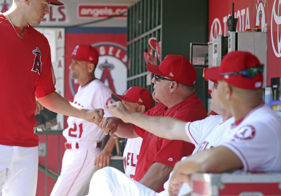 Los Angeles Angels manager Mike Scioscia, middle, fist-bumps players in the dugout before a baseball game between the Angels and the Oakland Athletics in Anaheim, Calif., Sunday, Sept. 30, 2018. It is expected that this will be Scioscia's last game as manager of the Angels. (AP Photo/Reed Saxon)