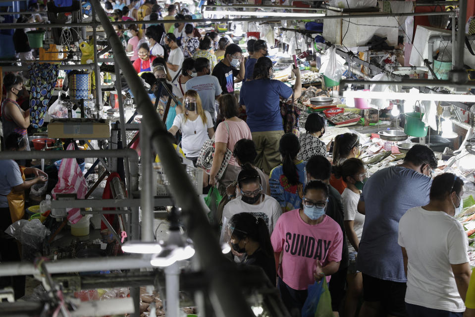 People wearing face masks and face shields to prevent the spread of the coronavirus buy food at the Munoz market in Quezon city, Philippines as they prepare for a stricter lockdown on Sunday March 28, 2021. The government will start stricter lockdown measures next week as the country struggles to control an alarming surge in COVID-19 cases. (AP Photo/Aaron Favila)