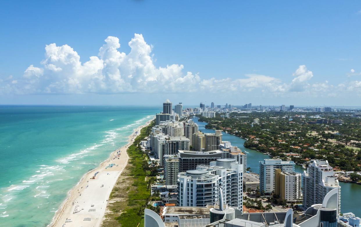 Looking down South Beach in Miami. Full view of the beach on the left and the city on the right. Beautiful blue sky on a clear day.