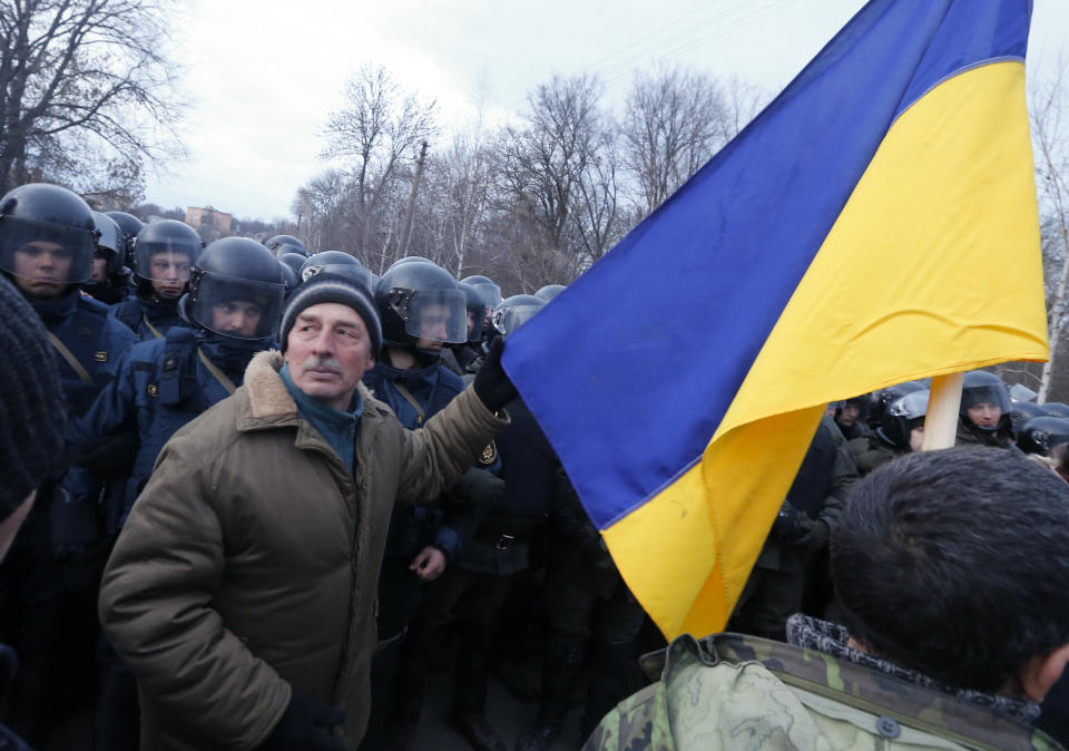 Protesters, who planned to stop buses carrying passengers evacuated from the Chinese city of Wuhan, speak to Ukrainian riot police blocking the road outside Novi Sarzhany, Ukraine, Thursday, Feb. 20, 2020. Several hundred residents in Ukraine's Poltava region protested to stop officials from quarantining the evacuees in their village because they feared becoming infected. Demonstrators put up road blocks and burned tires, while Ukrainian media reported that there were clashes with police, and more than 10 people were detained. (AP Photo/Efrem Lukatsky)