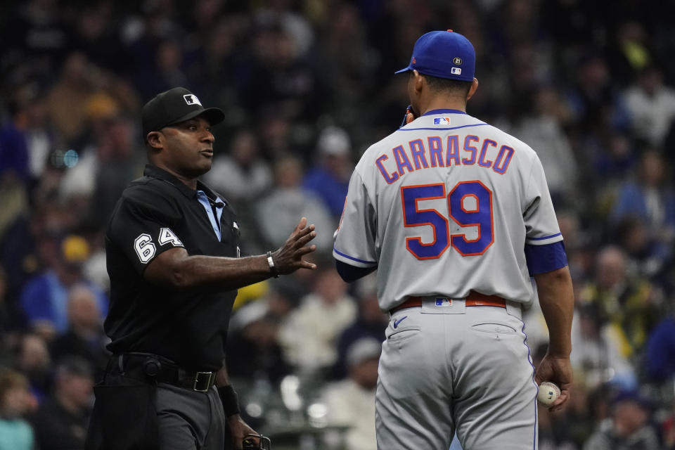 New York Mets' Carlos Carrasco (59) talks with umpire Alan Porter (64) during the fifth inning of a baseball game against the Milwaukee Brewers Monday, April 3, 2023, in Milwaukee. (AP Photo/Aaron Gash)