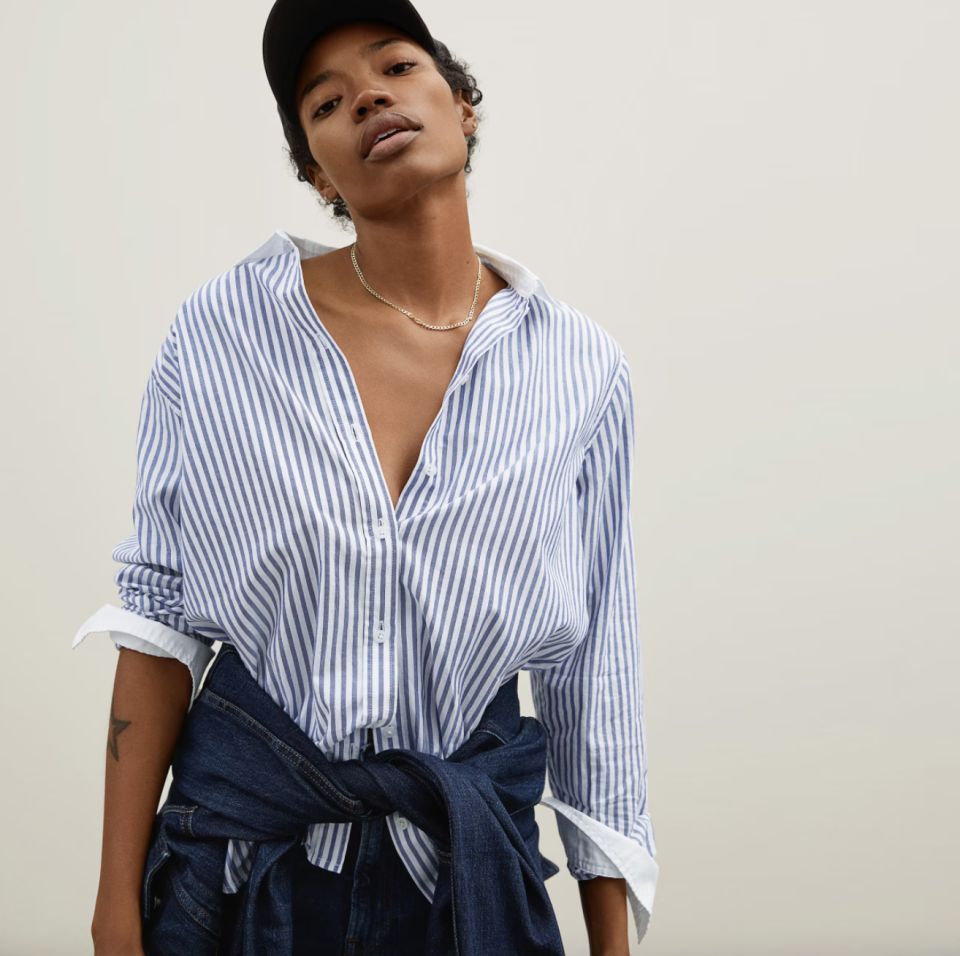 black model with short hair in  baseball cap and white and blue striped The Silky Cotton Relaxed Shirt (Photo via Everlane)