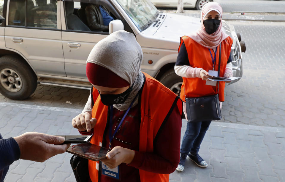 FILE - In this Feb. 10, 2021 file photo, poll workers from the Central Elections Commission register a local resident to the electoral roll, on the main road of Gaza City. Palestinian President Mahmoud Abbas' Fatah party and his militant Hamas rivals would each fall well short of a parliamentary majority if elections are held in May, forcing them to partner with each other or smaller parties to form a government, according to a poll released Tuesday, March 23, 2021, by the Palestinian Center for Policy and Survey Research. (AP Photo/Adel Hana, File)