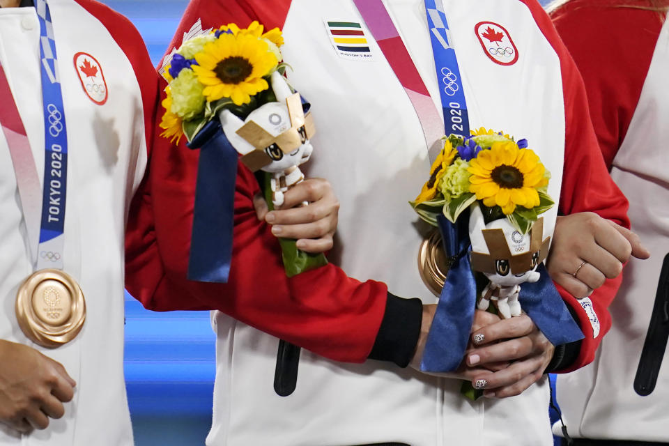 Canada team members hold flowers presented to medal winners at the medal ceremony for softball at the 2020 Summer Olympics, Wednesday, July 28, 2021, in Yokohama, Japan. (AP Photo/Sue Ogrocki)