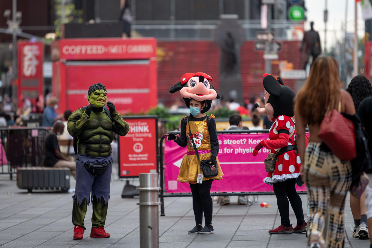 NEW YORK, NEW YORK - JULY 07: A woman wearing a Minnie Mouse costume wears a mask in Times Square as the city moves into Phase 3 of re-opening following restrictions imposed to curb the coronavirus pandemic on July 7, 2020 in New York City. Phase 3 permits the reopening of nail and tanning salons, tattoo parlors, spas and massages, dog runs and numerous other outdoor activities. Phase 3 is the third of four-phased stages designated by the state. (Photo by Alexi Rosenfeld/Getty Images)