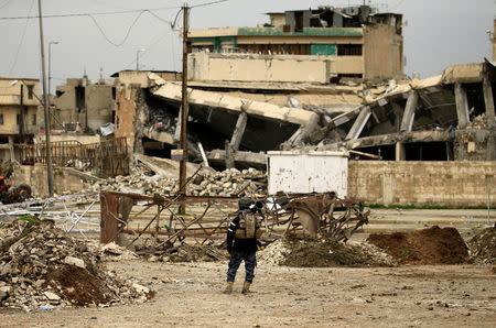 A federal policeman carries his weapon as he stands near buildings destroyed in clashes during a battle against Islamic State militants, in Mosul. REUTERS/Thaier Al-Sudani