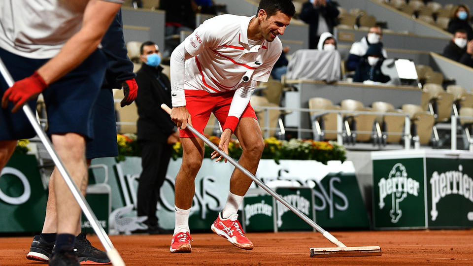 Novak Djokovic is pictured helping clean the court surface at Roland Garros during the French Open.