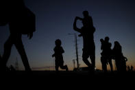 An Indian migrant laborer's family is silhouetted as they make the journey to their village by foot, following a lockdown amid concern over spread of coronavirus in New Delhi, India, Saturday, March 28, 2020. Authorities sent a fleet of buses to the outskirts of India's capital on Saturday to meet an exodus of migrant workers desperately trying to reach their home villages during the world's largest coronavirus lockdown. Thousands of people, mostly young male day laborers but also families, fled their New Delhi homes after Prime Minister Narendra Modi announced a 21-day lockdown that began on Wednesday and effectively put millions of Indians who live off daily earnings out of work. (AP Photo/Altaf Qadri)